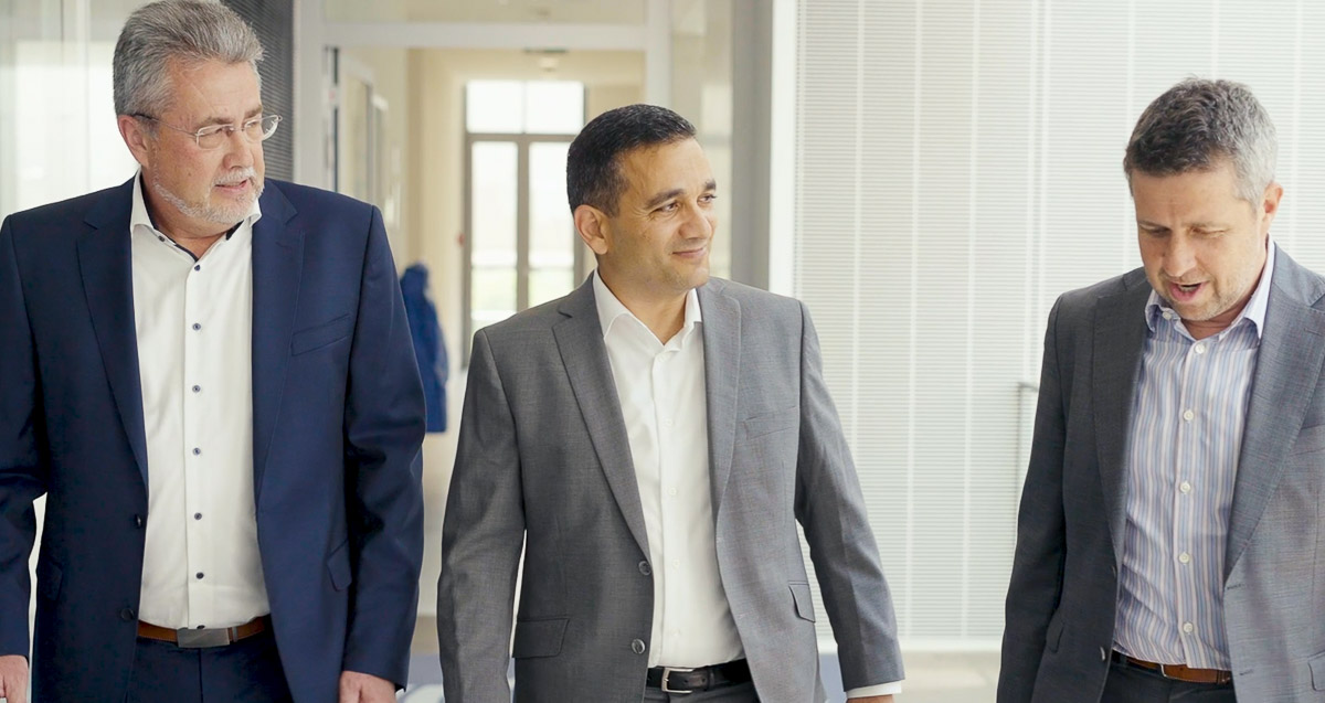 Three men in business suits walking down a hallway.