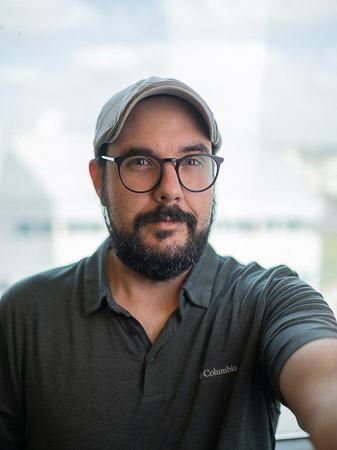 A bearded man wearing glasses and a polo shirt.